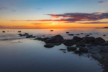 Kayalık bir sahil üzerinde kırmızı renkli gökyüzü. Gün batımı manzarası.