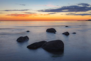 Kayalık bir sahil üzerinde kırmızı renkli gökyüzü. Gün batımı manzarası.