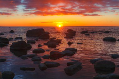 Sığ manzaranın güzel manzarası kayalık kıyılarda kızıl renkli günbatımında, Baltık Denizi