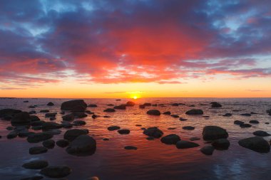 Sığ manzaranın güzel manzarası kayalık kıyılarda kızıl renkli günbatımında, Baltık Denizi
