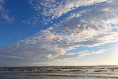 Denizin üzerinde mavi gökyüzünde güneş parlıyor.