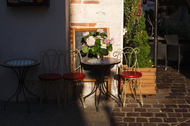 Sandalyeler ve masa duvar boyunca gölgelerde. Avrupa 'da bir açık kafe..