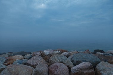 Kötü havada ve sisli bir günde, kayalık deniz kıyısı. Hüzünlü.