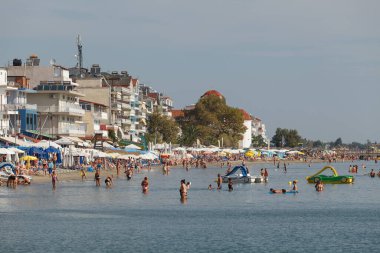 PARALYA, GREECE 10 Eylül 2018: sahil sahnesi. İnsanlar ucuz otellerle dolu sığ sularda yüzüyor ve güneşleniyor.