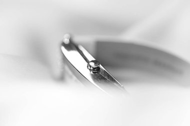 Close up view of silver metal watch wrapped in the white satin cloth in monochrome.