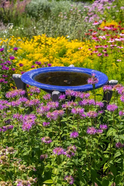 Blue fountain base in the middle of flower garden in Denver botanical gardens.
