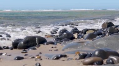 Pasifik Okyanusu dalgaları Moolack sahilinde siyah kayalara çarpıyor.