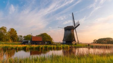 Hollanda 'nın tarihi yel değirmeni alacakaranlık altında dramatik gökyüzü.