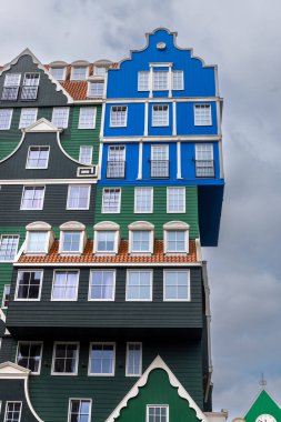 Hollanda Zaandam 'da gökyüzü bulutlu modern mavi ve yeşil renkli geleneksel Hollanda tarzı binalar.