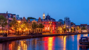 HAARLEM, NETHERLANDS - 20 Mayıs 2023: Alacakaranlıkta Binnen Spaame nehri boyunca renkli ışıklandırmayla Harlem şehri.