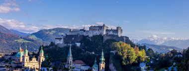 Mavi gökyüzüne karşı Hohensalzburg Kalesi 'nin panoramik manzarası, bir tepenin üstündeki büyük bir ortaçağ kalesi Salzburg şehrini izliyor..