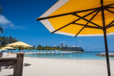 Yaz mevsiminde Karayip adalarında plaj manzarası ve sarı şemsiye.
