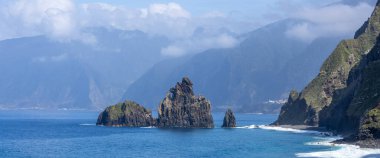 Madeira Adası Praia da Ribeira da Janela 'daki yüksek volkanik kaya oluşumlarının manzaralı manzarası.