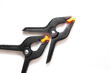 Beyaz arka planda iki siyah ağır plastik kıskaç..