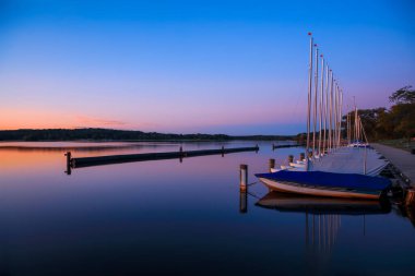 Scenic landscape of many sail boats at Kensington metro park in Michigan during twilight.