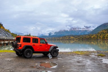 Seward, Alaska, ABD - Sep 21,2024,: Alaska manzaralı göl kıyısında bir Orange 4x4 Jeep.