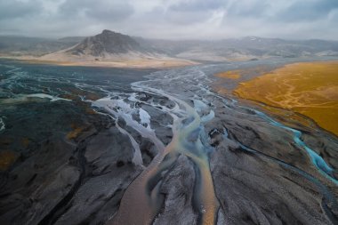 Baharda İzlanda kırsalındaki manzaralı nehir ve dağ manzarası.