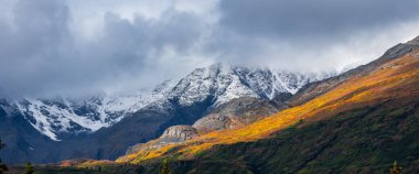 Scenic panoramic landscape of snow covered mountains along Denali highway in Alaska. clipart