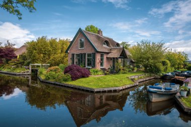 Hollanda 'nın ünlü Giethoorn köyündeki kanalların yanındaki çatı evler bahar zamanı.