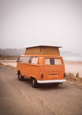 LAKESIDE, OREGON - 3 Temmuz 2023: Oregon Pasifik sahilindeki deniz kıyısında sarı bir vintage karavan.