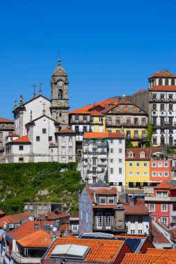 Portekiz 'in Porto şehrindeki tarihi renkli binalar ve yüksek kilise güneşli bir günde.