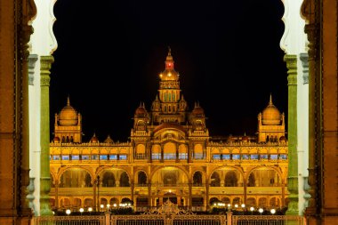 Tarihsel Mysore Maharaja sarayı gece vakti altın parıltıyla aydınlatılmış, ön girişten manzara.