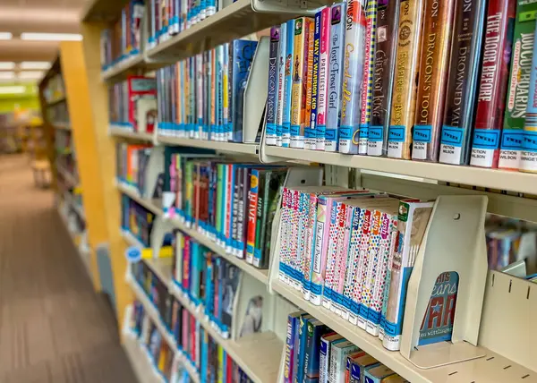 Novi, Michigan - 31 Temmuz 2021: Michigan 'daki Novi halk kütüphanesinde öğrenci kitapları ve roman rafları.