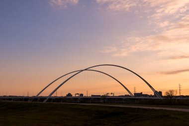 Dallas 'taki Margaret McDermott Köprüsü Trinity nehri üzerinde alacakaranlık gökyüzünün altında.