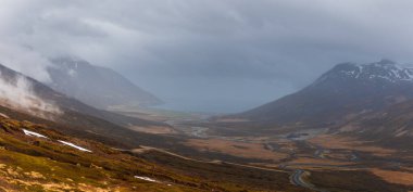 Tundra 'nın ortasındaki İzlanda manzaralı bulutlu dağların panoramik manzarası.