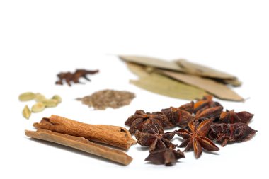 Beyaz zemin üzerinde çeşitli organik baharatların yakın görünümü.