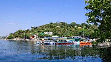 Udaipur, Rajasthan, Hindistan - 17 Ekim 2022: Udaipur, Rajasthan, Hindistan 'daki Pichola Gölü kıyısındaki renkli turist tekneleri