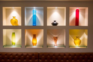 İç dekorasyon için rafta ışık altında aydınlatılmış sekiz farklı cam kavanoz..