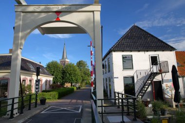 Baard, Friesland, Hollanda 'da Leeuwarden' dan 13 km batıda bulunan ve arka planda kilisenin çan kulesinin bulunduğu tarihi evler ve bir asma köprü (Dekema Brege) bulunuyor.