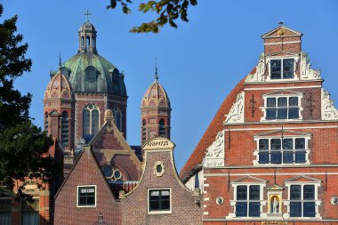 The colorful facades of historic houses located along Kerkstraat street in the city center of Hoorn, West Friesland, Netherlands, with the Butter House (Boterhal, built in 1563) on the right, and the Dome and turrets of Koepelkerk church  clipart