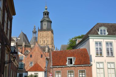 Traditional historic medieval houses in the old picturesque town of Zutphen, Gelderland, Netherlands, with the bell tower of Saint Walburgiskerk church in the background clipart