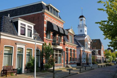 Traditional houses and a little church located along Legeweg street in the historic center of Dokkum, Friesland, Netherlands clipart