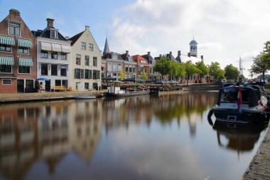 Arka planda 1610 yılında inşa edilen Oud Stadhuis (Eski Belediye Binası) ile, Dokkum, Friesland, Hollanda 'daki küçük kanal (klein Diep) üzerindeki geleneksel evler, mavnalar ve teknelerin yansımaları