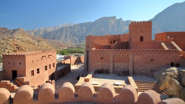 Etkileyici Nakhal kalesi, Al Batinah, Umman, kuleleri ve surlarıyla, palmiye koruluğuna bakan ve dağlarla çevrili