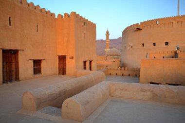 Nizwa 'daki etkileyici Nizwa kalesi, Al Dakhiliyah, Umman, arka planda cami minaresi.