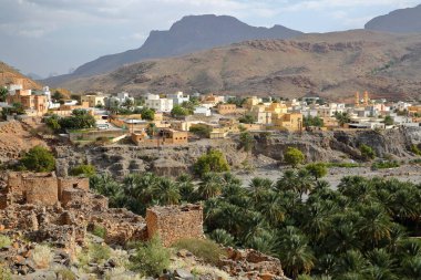 Al Hamra 'nın 12 km batısında yer alan Ghul köyü ve Jebel Shams yolu üzerindeki Al Dakhiliyah, Umman, Ghul köyünün kalıntıları ön planda ve yemyeşil tarih plantasyonları ile