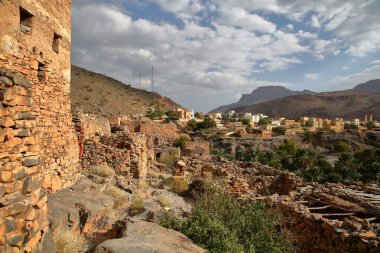 Ghul village, located 12 km west of Al Hamra and on the road to Jebel Shams, Al Dakhiliyah, Oman, with the ruins of the abandoned old Ghul village in the foreground  clipart