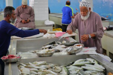 MUTTRAH, MUSCAT, OMAN - DECEMBER 27, 2024: The Muttrah morning fish market with local sellers and customers traditionally dressed clipart