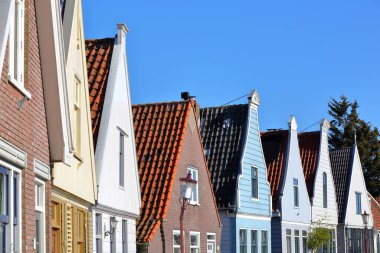 A row of colorful and traditional wooden houses in the village of Durgerdam, North Holland, Netherlands, located near Amsterdam along the dyke of the IJmeer (IJ lake)