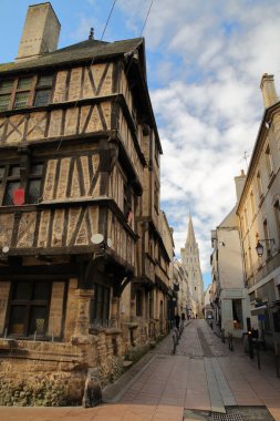 Bayeux, Calvados, Normandiya, Fransa 'daki Cuisiniers caddesinde yarım keresteli bir ortaçağ evi ve arka planda Notre Dame Katedrali (çan kulesi) bulunuyor.