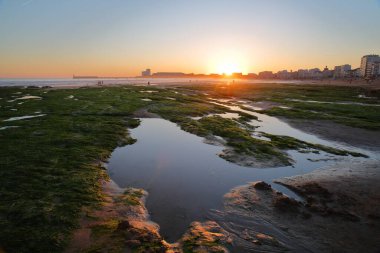 Gün batımında Les Sables d 'Olonne, Vendee, Fransa' da sahil, arka planda deniz feneri ve şehir