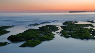 Sahilde gün batımında Les Sables d 'Olonne, Vendee, Fransa' da, iskele ve deniz feneri arka planda.