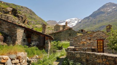 Bonneval sur Arc, Vanoise Ulusal Parkı, Maurienne Vadisi, Savoie, Kuzey Fransız Alpleri, Fransa 'nın kuzeyindeki bir köy olan L' Ecot 'ta evler ve dağlarla çevrili geleneksel tahta çatılar bulunmaktadır.