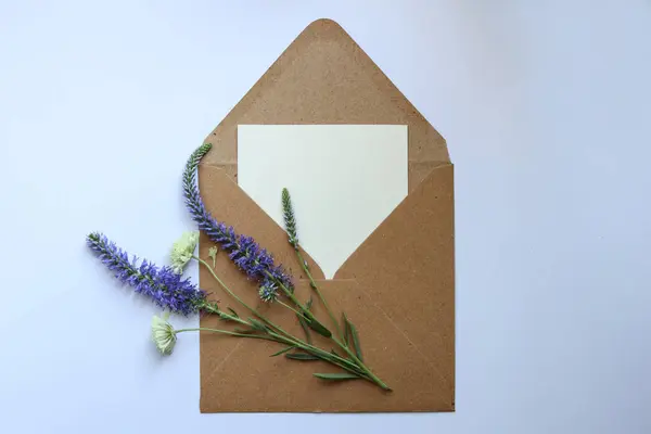 茶色の封筒に 白いメッセージカードと 野生の花が — ストック写真