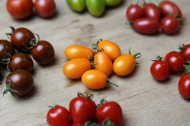 Tahta bir masanın üzerinde çeşitli taze domatesler var.