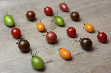 Tahta bir masanın üzerinde çeşitli taze domatesler var.